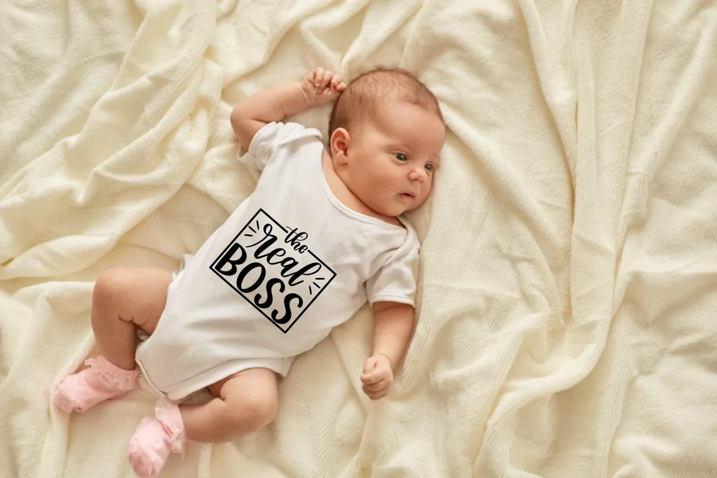 newborn-baby-girl-boy-lying-blanket-bed-looking-away-wearing-white-bodysuit-socks-infant-studying-world-around-has-sleepy-expression