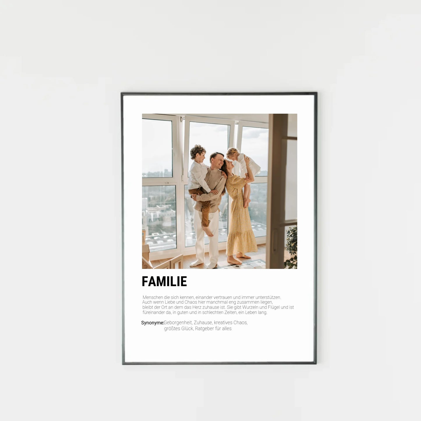 Poster mit personalisierbarem Foto in schwarzem Holzrahmen. Unten groß ‚FAMILIE‘ mit Definition im Wörterbuchstil: Menschen, die sich kennen, vertrauen, unterstützen und gemeinsam durch Liebe und Chaos gehen. Familie gibt Wurzeln und Flügel, ist immer da – in guten wie in schlechten Zeiten. Synonyme: Geborgenheit, Zuhause, kreatives Chaos, größtes Glück, Ratgeber für alles.