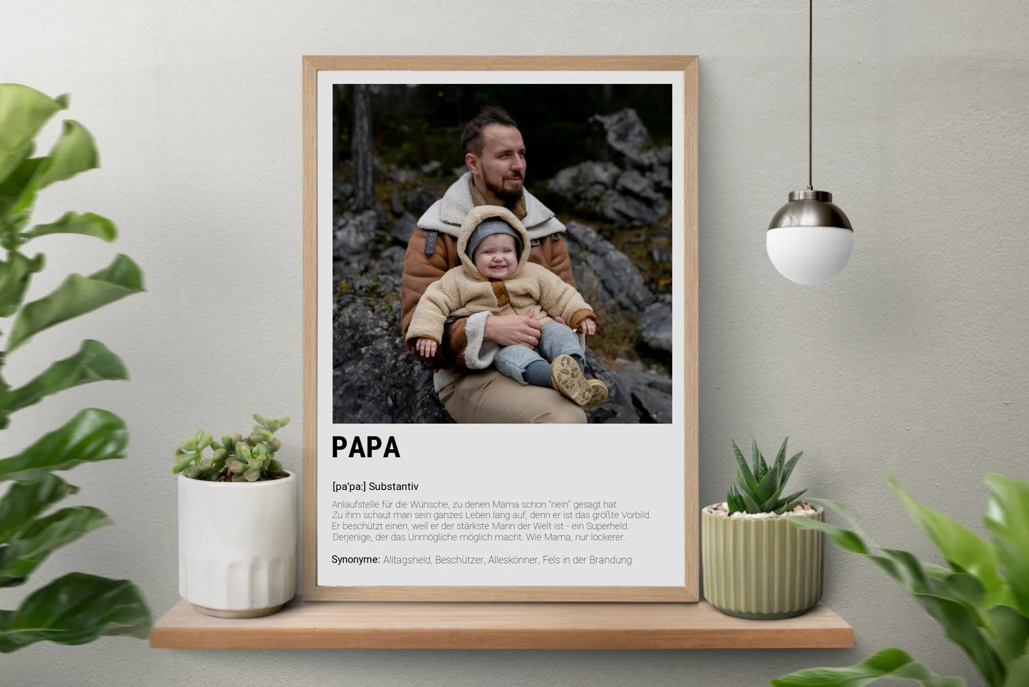 Poster personalisierbarem Foto-Bereich im oberen Teil in einem hellem Holzrahmen. Darunter steht groß das Wort ‚PAPA‘ mit einer Definition in Wörterbuch-Stil. Beschrieben wird der Vater als Alltagsheld, Beschützer, Alleskönner und Fels in der Brandung