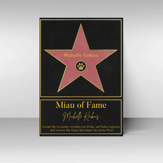 Poster im Stil eines ‚Walk of Fame‘-Sterns. In der Mitte ein rosa Stern mit gelbem Rand und Pfotenabdruck-Symbol, dazu ein personalisierbarer Name. Darunter der Titel ‚Miau of Fame‘ mit Namensfeld. Text: Geehrt für Leckerlis verteilen wie Profis, auf Sofas regieren und wissen: Die Katze hat immer das letzte Wort.