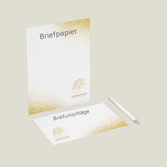 Briefpapier und ein passender Briefumschlag mit „FamilySurprise“-Logo und goldfarbenem Verlauf, daneben ein Stift.