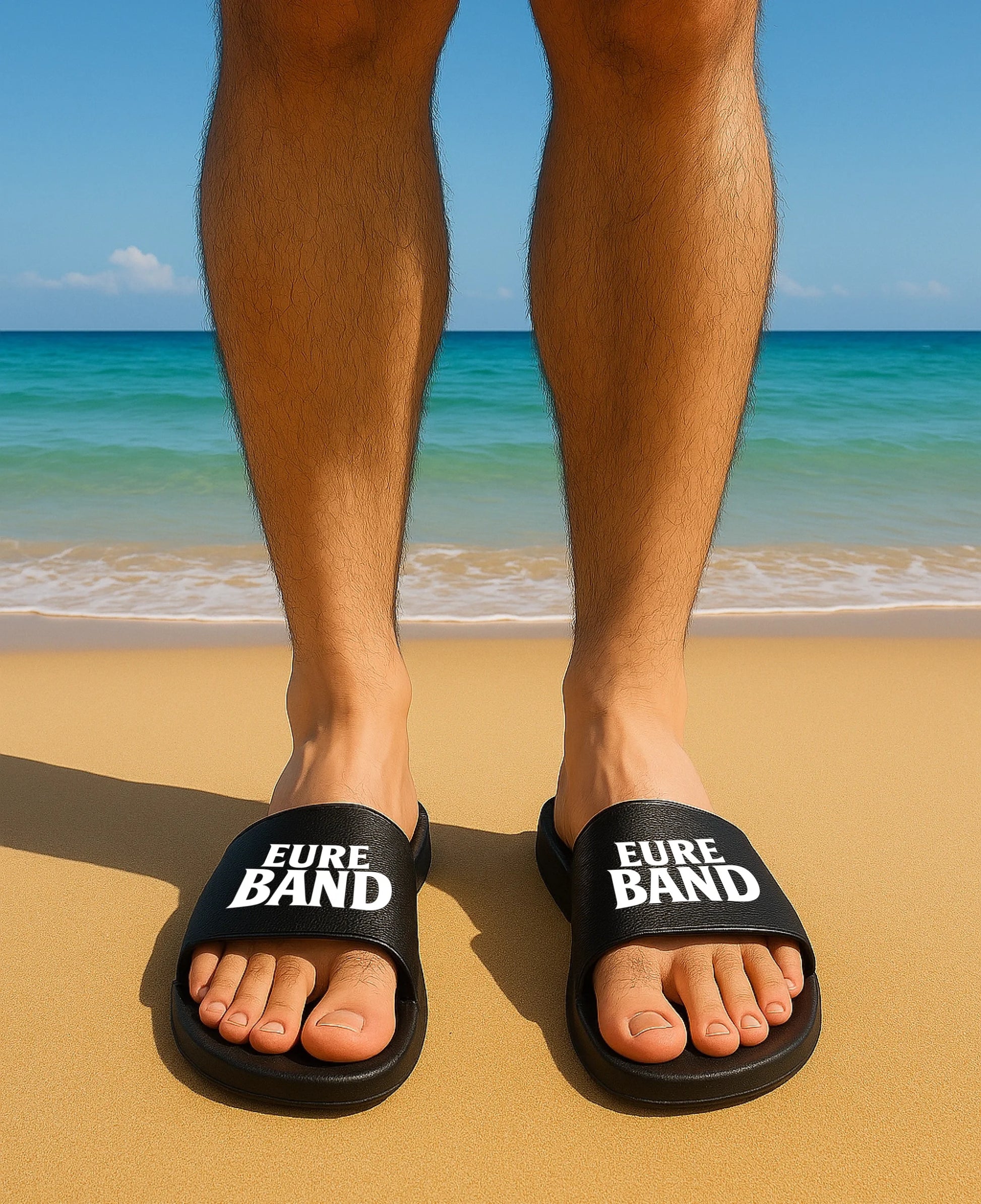 Schwarze Badelatschen mit breitem Riemen. Auf beiden Riemen ist in weißen Buchstaben der Schriftzug ‚Eure Band‘ aufgedruckt. Der Text kann individuell mit dem eigenen Bandnamen gestaltet werden.
