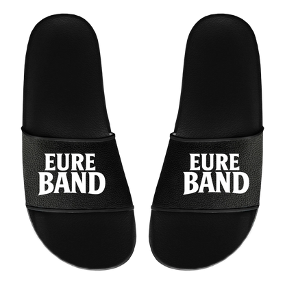 Schwarze Badelatschen mit breitem Riemen. Auf beiden Riemen ist in weißen Buchstaben der Schriftzug ‚Eure Band‘ aufgedruckt. Der Text kann individuell mit dem eigenen Bandnamen gestaltet werden.