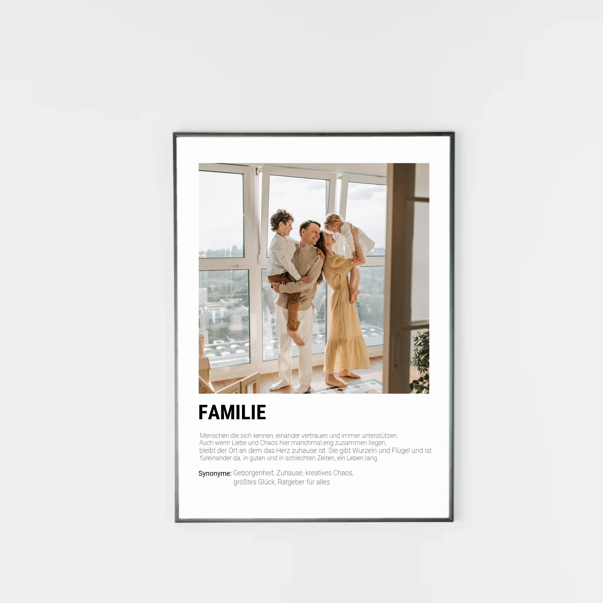Poster mit personalisierbarem Foto in schwarzem Holzrahmen. Unten groß ‚FAMILIE‘ mit Definition im Wörterbuchstil: Menschen, die sich kennen, vertrauen, unterstützen und gemeinsam durch Liebe und Chaos gehen. Familie gibt Wurzeln und Flügel, ist immer da – in guten wie in schlechten Zeiten. Synonyme: Geborgenheit, Zuhause, kreatives Chaos, größtes Glück, Ratgeber für alles.