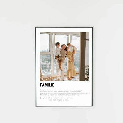Poster mit personalisierbarem Foto in schwarzem Holzrahmen. Unten groß ‚FAMILIE‘ mit Definition im Wörterbuchstil: Menschen, die sich kennen, vertrauen, unterstützen und gemeinsam durch Liebe und Chaos gehen. Familie gibt Wurzeln und Flügel, ist immer da – in guten wie in schlechten Zeiten. Synonyme: Geborgenheit, Zuhause, kreatives Chaos, größtes Glück, Ratgeber für alles.
