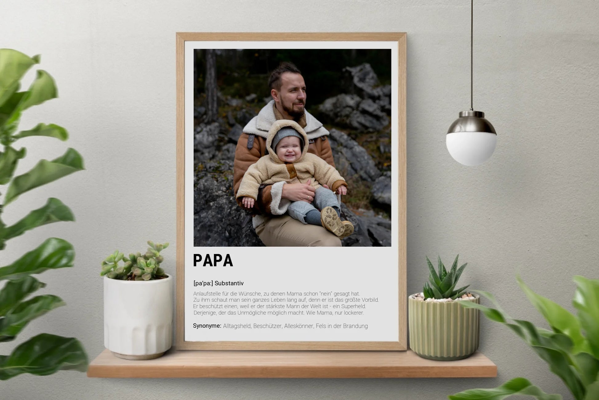 Poster personalisierbarem Foto-Bereich im oberen Teil in einem hellem Holzrahmen. Darunter steht groß das Wort ‚PAPA‘ mit einer Definition in Wörterbuch-Stil. Beschrieben wird der Vater als Alltagsheld, Beschützer, Alleskönner und Fels in der Brandung