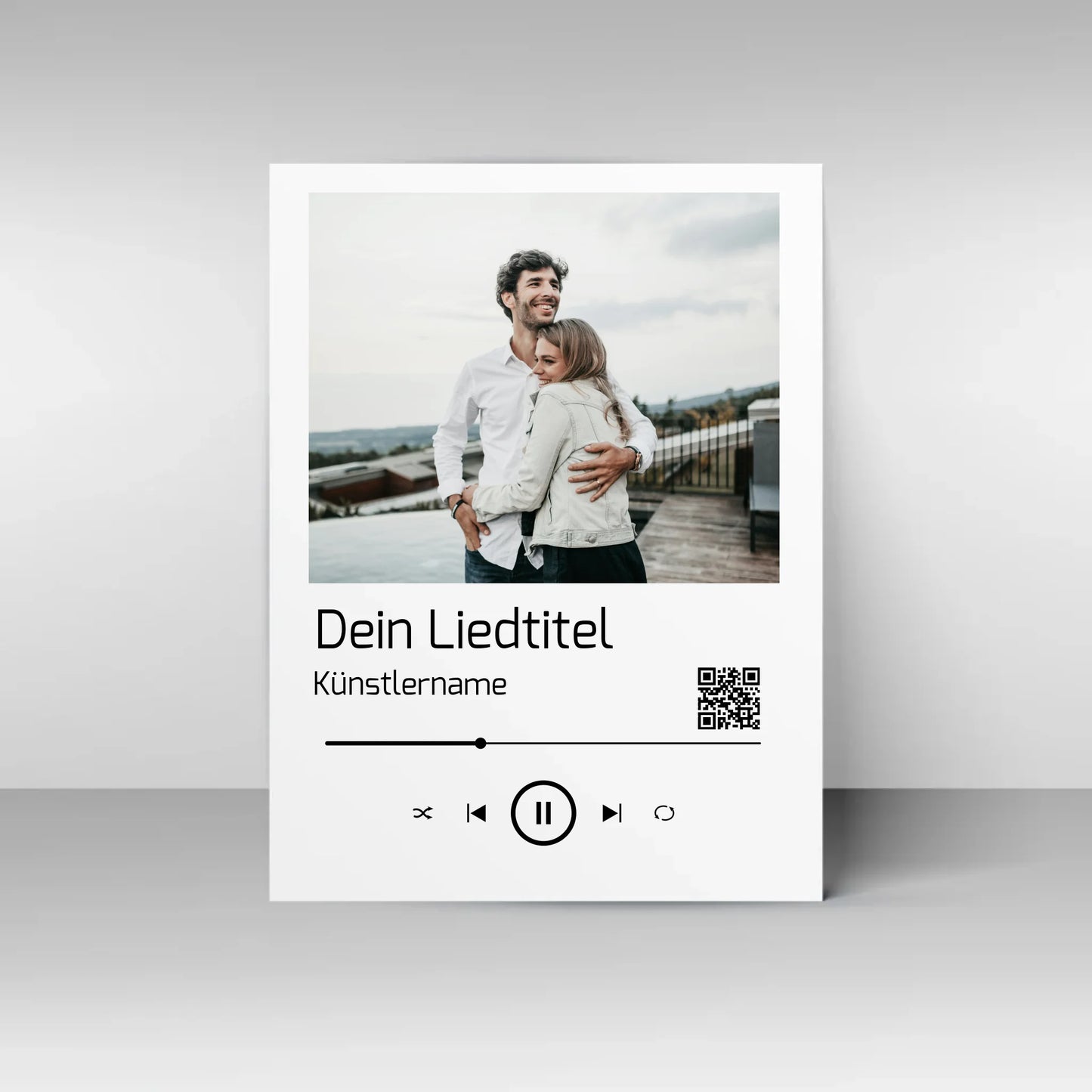 Poster im Stil einer Musik-App mit personalisierbarem Foto oben. Darunter Platz für individuellen Liedtitel, Künstlername und einen QR-Code, der direkt zu Spotify führt. Unten grafische Symbole einer Musiksteuerung wie Play, Pause und Skip.