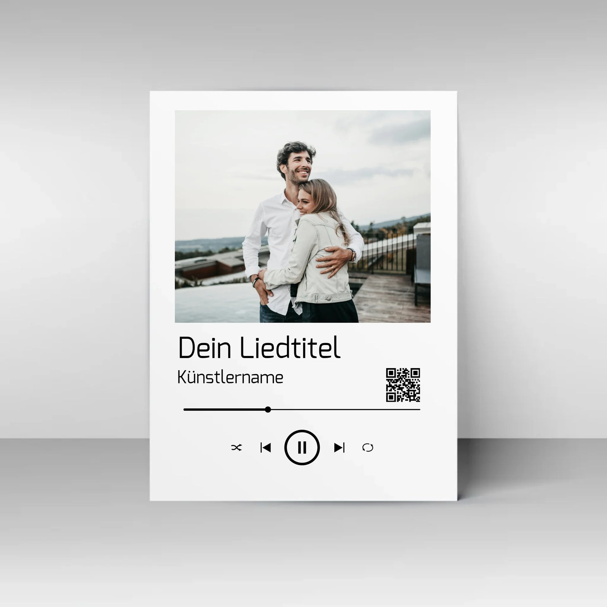 Poster im Stil einer Musik-App mit personalisierbarem Foto oben. Darunter Platz für individuellen Liedtitel, Künstlername und einen QR-Code, der direkt zu Spotify führt. Unten grafische Symbole einer Musiksteuerung wie Play, Pause und Skip.