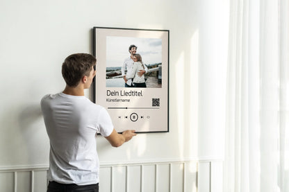 Poster im Stil einer Musik-App mit personalisierbarem Foto oben. Darunter Platz für individuellen Liedtitel, Künstlername und einen QR-Code, der direkt zu Spotify führt. Unten grafische Symbole einer Musiksteuerung wie Play, Pause und Skip.