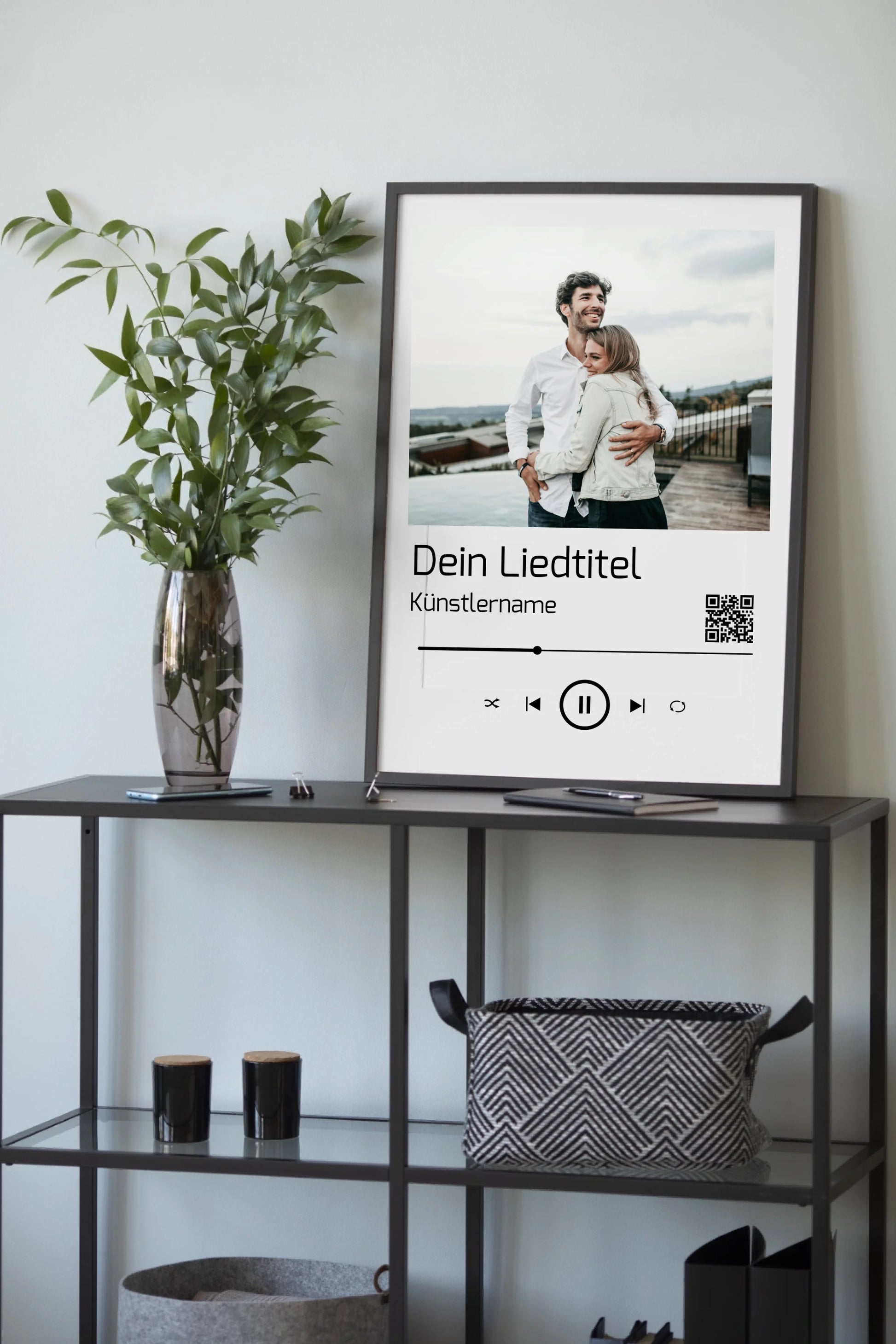 Poster im Stil einer Musik-App mit personalisierbarem Foto oben. Darunter Platz für individuellen Liedtitel, Künstlername und einen QR-Code, der direkt zu Spotify führt. Unten grafische Symbole einer Musiksteuerung wie Play, Pause und Skip.