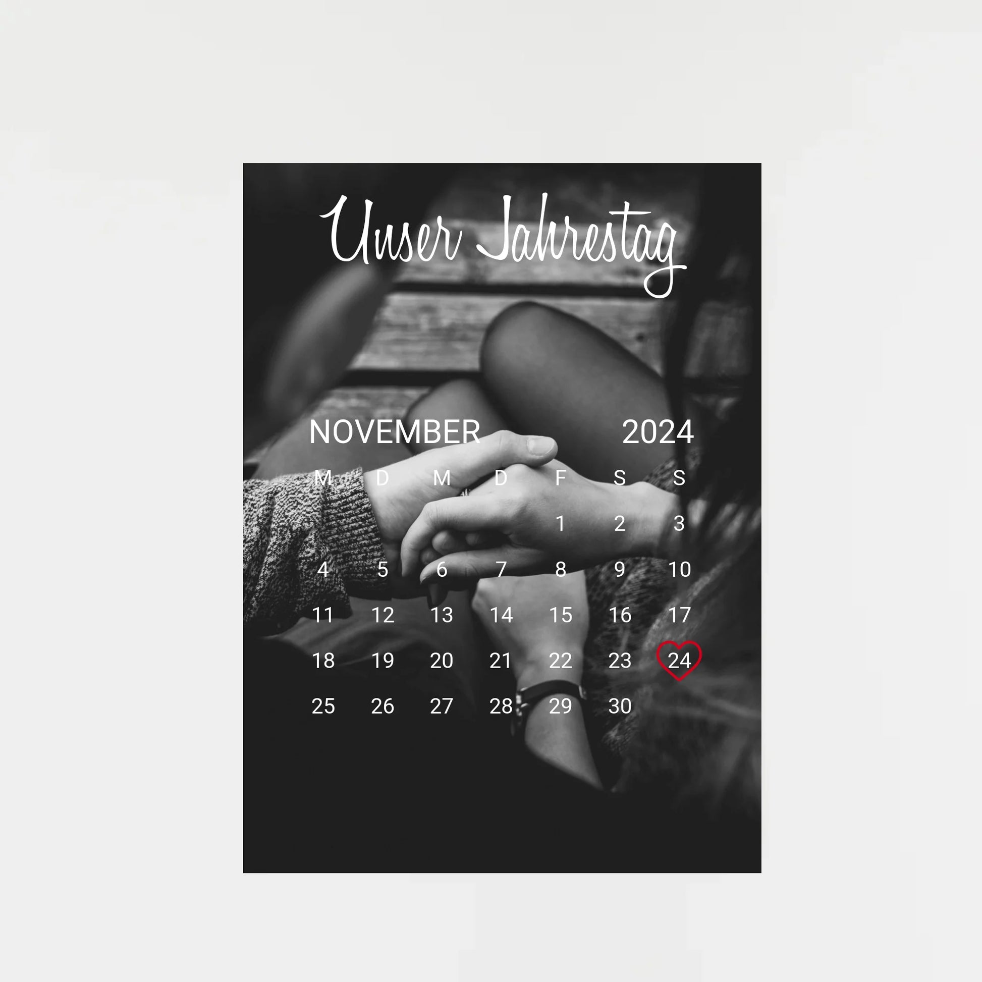 Poster im Kalender-Design mit schwarz-weißem Hintergrundfoto, hier als Beispiel zwei sich haltende Hände. Oben die feste Überschrift ‚Unser Jahrestag‘. Monat, Jahr und Tag sind personalisierbar, der ausgewählte Tag wird mit einem Herz markiert. Hintergrundfoto ist ebenfalls personalisierbar.