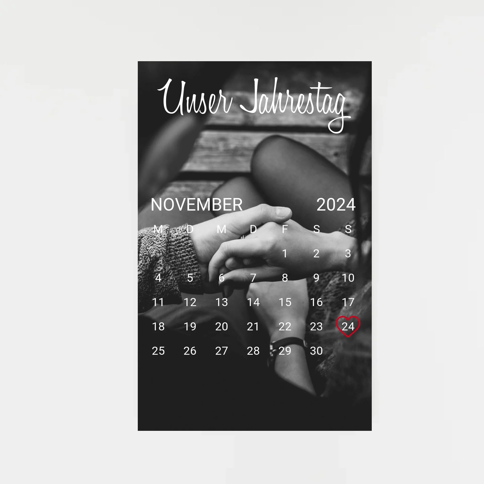 Poster im Kalender-Design mit schwarz-weißem Hintergrundfoto, hier als Beispiel zwei sich haltende Hände. Oben die feste Überschrift ‚Unser Jahrestag‘. Monat, Jahr und Tag sind personalisierbar, der ausgewählte Tag wird mit einem Herz markiert. Hintergrundfoto ist ebenfalls personalisierbar.