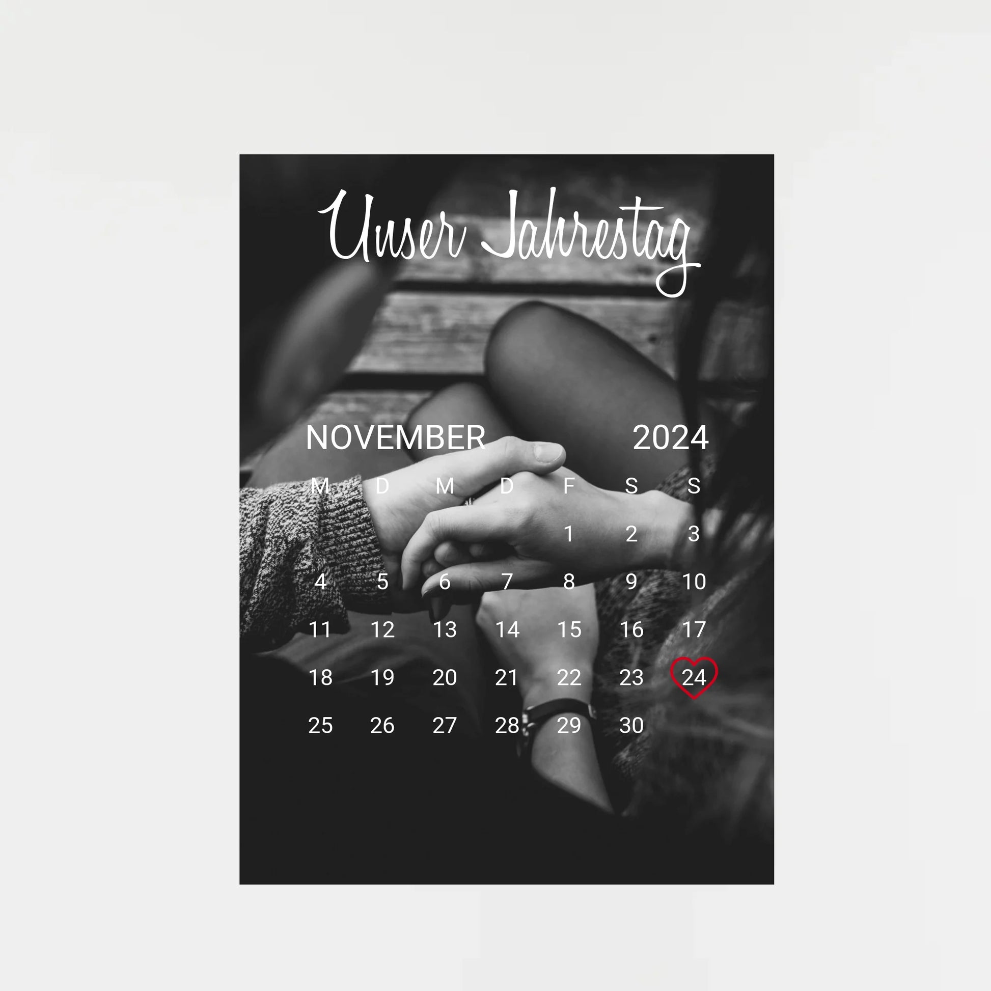 Poster im Kalender-Design mit schwarz-weißem Hintergrundfoto, hier als Beispiel zwei sich haltende Hände. Oben die feste Überschrift ‚Unser Jahrestag‘. Monat, Jahr und Tag sind personalisierbar, der ausgewählte Tag wird mit einem Herz markiert. Hintergrundfoto ist ebenfalls personalisierbar.