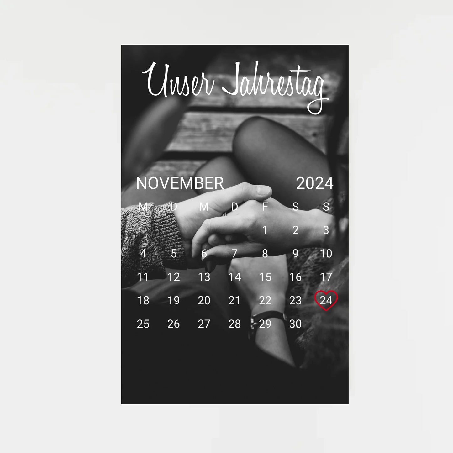 Poster im Kalender-Design mit schwarz-weißem Hintergrundfoto, hier als Beispiel zwei sich haltende Hände. Oben die feste Überschrift ‚Unser Jahrestag‘. Monat, Jahr und Tag sind personalisierbar, der ausgewählte Tag wird mit einem Herz markiert. Hintergrundfoto ist ebenfalls personalisierbar.