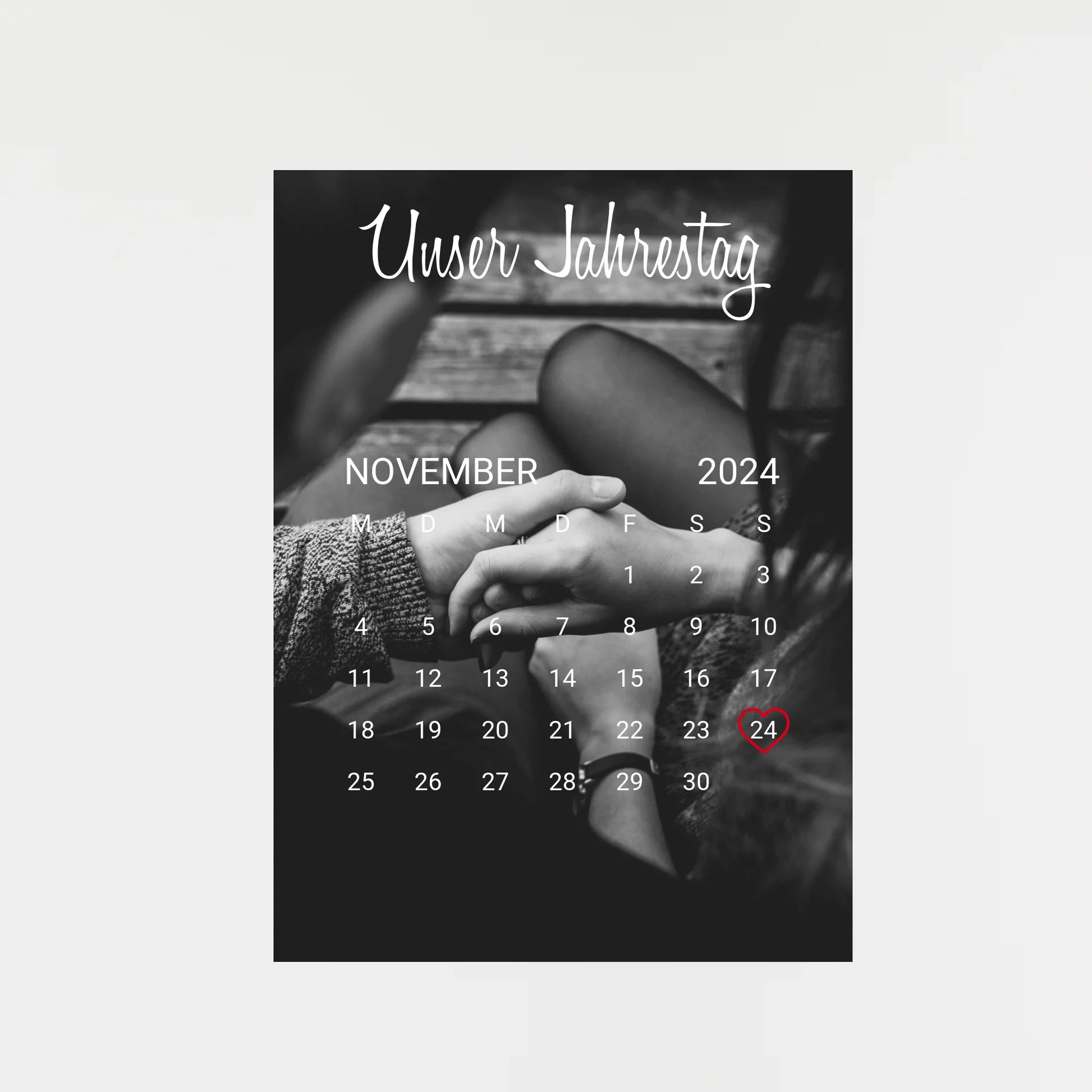 Poster im Kalender-Design mit schwarz-weißem Hintergrundfoto, hier als Beispiel zwei sich haltende Hände. Oben die feste Überschrift ‚Unser Jahrestag‘. Monat, Jahr und Tag sind personalisierbar, der ausgewählte Tag wird mit einem Herz markiert. Hintergrundfoto ist ebenfalls personalisierbar.