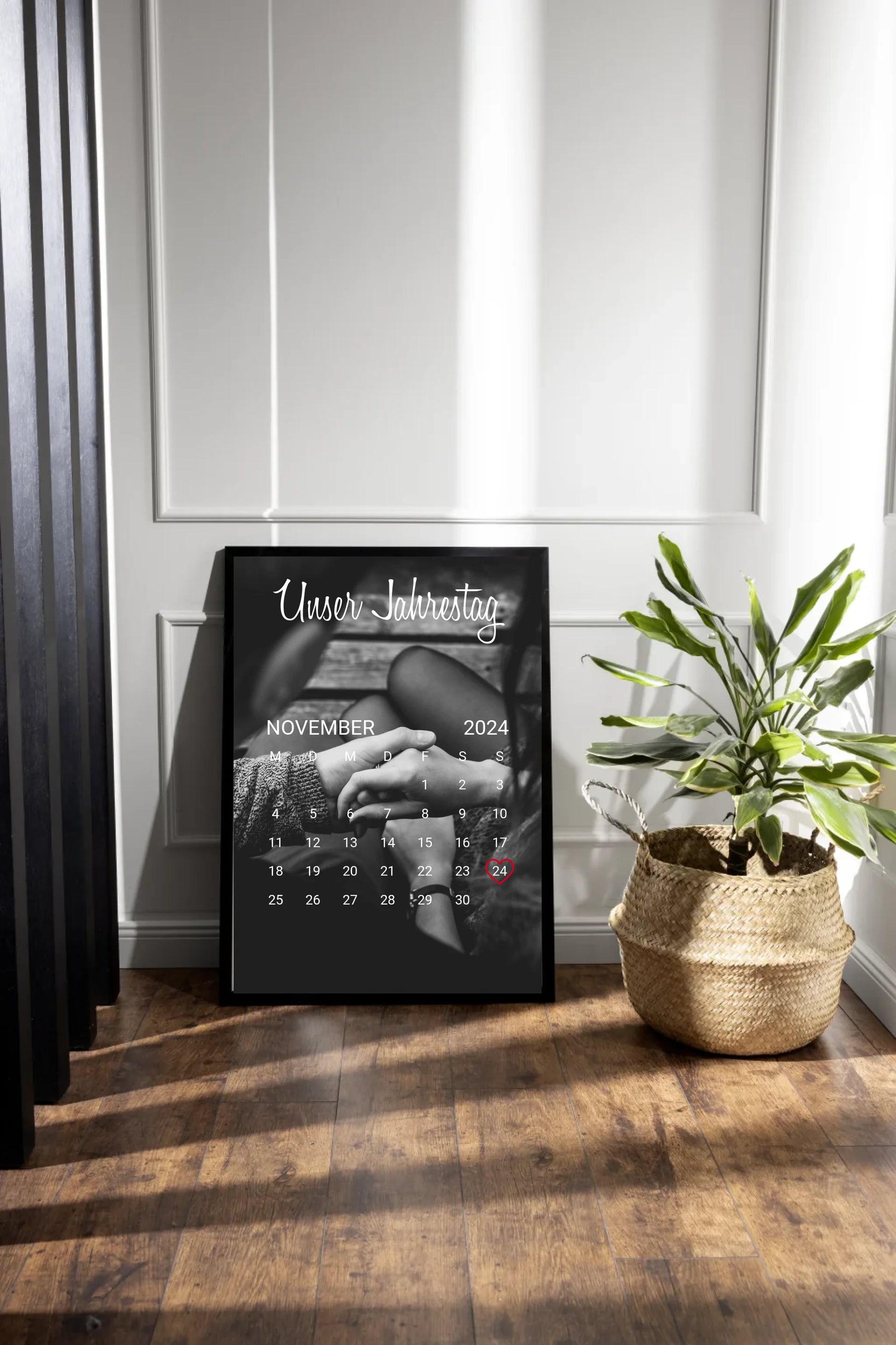Poster im Kalender-Design mit schwarz-weißem Hintergrundfoto, hier als Beispiel zwei sich haltende Hände. Oben die feste Überschrift ‚Unser Jahrestag‘. Monat, Jahr und Tag sind personalisierbar, der ausgewählte Tag wird mit einem Herz markiert. Hintergrundfoto ist ebenfalls personalisierbar.