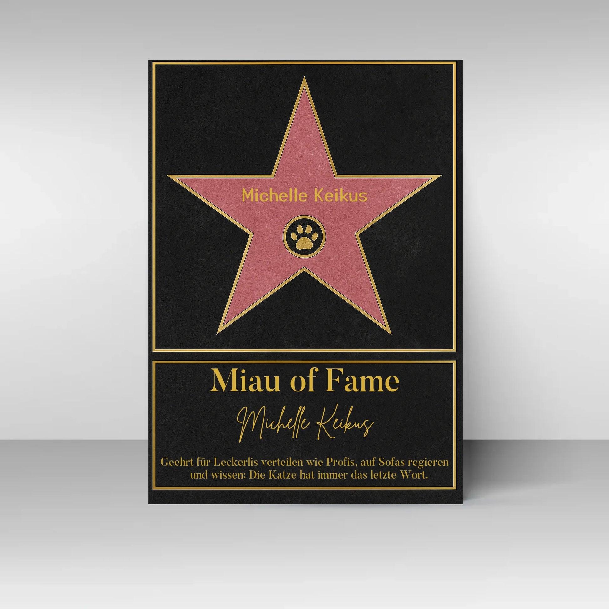 Poster im Stil eines ‚Walk of Fame‘-Sterns. In der Mitte ein rosa Stern mit gelbem Rand und Pfotenabdruck-Symbol, dazu ein personalisierbarer Name. Darunter der Titel ‚Miau of Fame‘ mit Namensfeld. Text: Geehrt für Leckerlis verteilen wie Profis, auf Sofas regieren und wissen: Die Katze hat immer das letzte Wort.