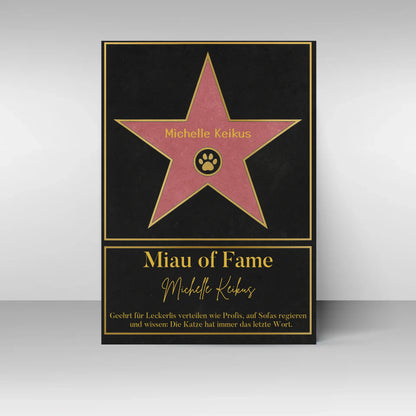 Poster im Stil eines ‚Walk of Fame‘-Sterns. In der Mitte ein rosa Stern mit gelbem Rand und Pfotenabdruck-Symbol, dazu ein personalisierbarer Name. Darunter der Titel ‚Miau of Fame‘ mit Namensfeld. Text: Geehrt für Leckerlis verteilen wie Profis, auf Sofas regieren und wissen: Die Katze hat immer das letzte Wort.