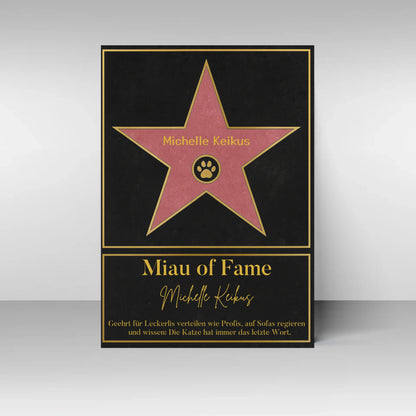 Poster im Stil eines ‚Walk of Fame‘-Sterns. In der Mitte ein rosa Stern mit gelbem Rand und Pfotenabdruck-Symbol, dazu ein personalisierbarer Name. Darunter der Titel ‚Miau of Fame‘ mit Namensfeld. Text: Geehrt für Leckerlis verteilen wie Profis, auf Sofas regieren und wissen: Die Katze hat immer das letzte Wort.