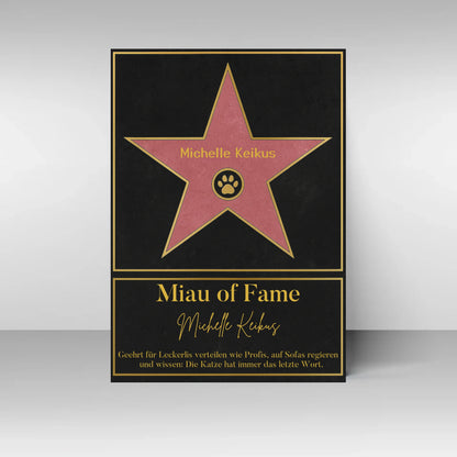 Poster im Stil eines ‚Walk of Fame‘-Sterns. In der Mitte ein rosa Stern mit gelbem Rand und Pfotenabdruck-Symbol, dazu ein personalisierbarer Name. Darunter der Titel ‚Miau of Fame‘ mit Namensfeld. Text: Geehrt für Leckerlis verteilen wie Profis, auf Sofas regieren und wissen: Die Katze hat immer das letzte Wort.