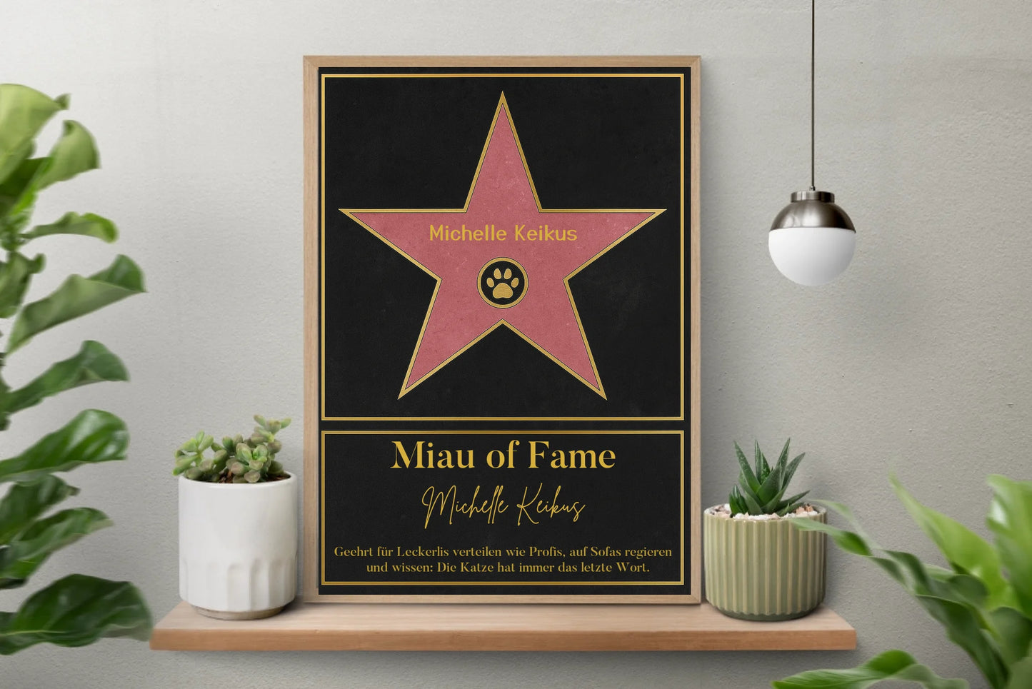 Poster im Stil eines ‚Walk of Fame‘-Sterns. In der Mitte ein rosa Stern mit gelbem Rand und Pfotenabdruck-Symbol, dazu ein personalisierbarer Name. Darunter der Titel ‚Miau of Fame‘ mit Namensfeld. Text: Geehrt für Leckerlis verteilen wie Profis, auf Sofas regieren und wissen: Die Katze hat immer das letzte Wort.