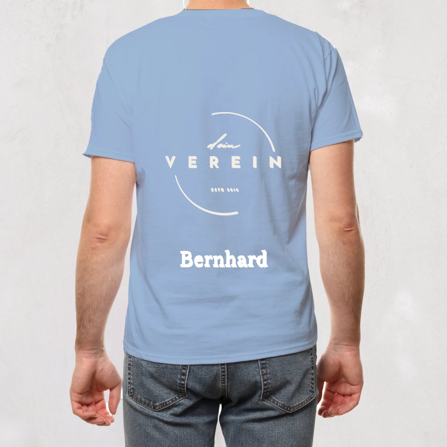 hellblaues T-Shirt mit Vereinslogo und dem Schriftzug ‚dein Verein – seit 2018‘ auf der Rückseite. Unterhalb des Logos steht ein personalisierbarer Name. Vereinsname und Name können individuell angepasst werden.