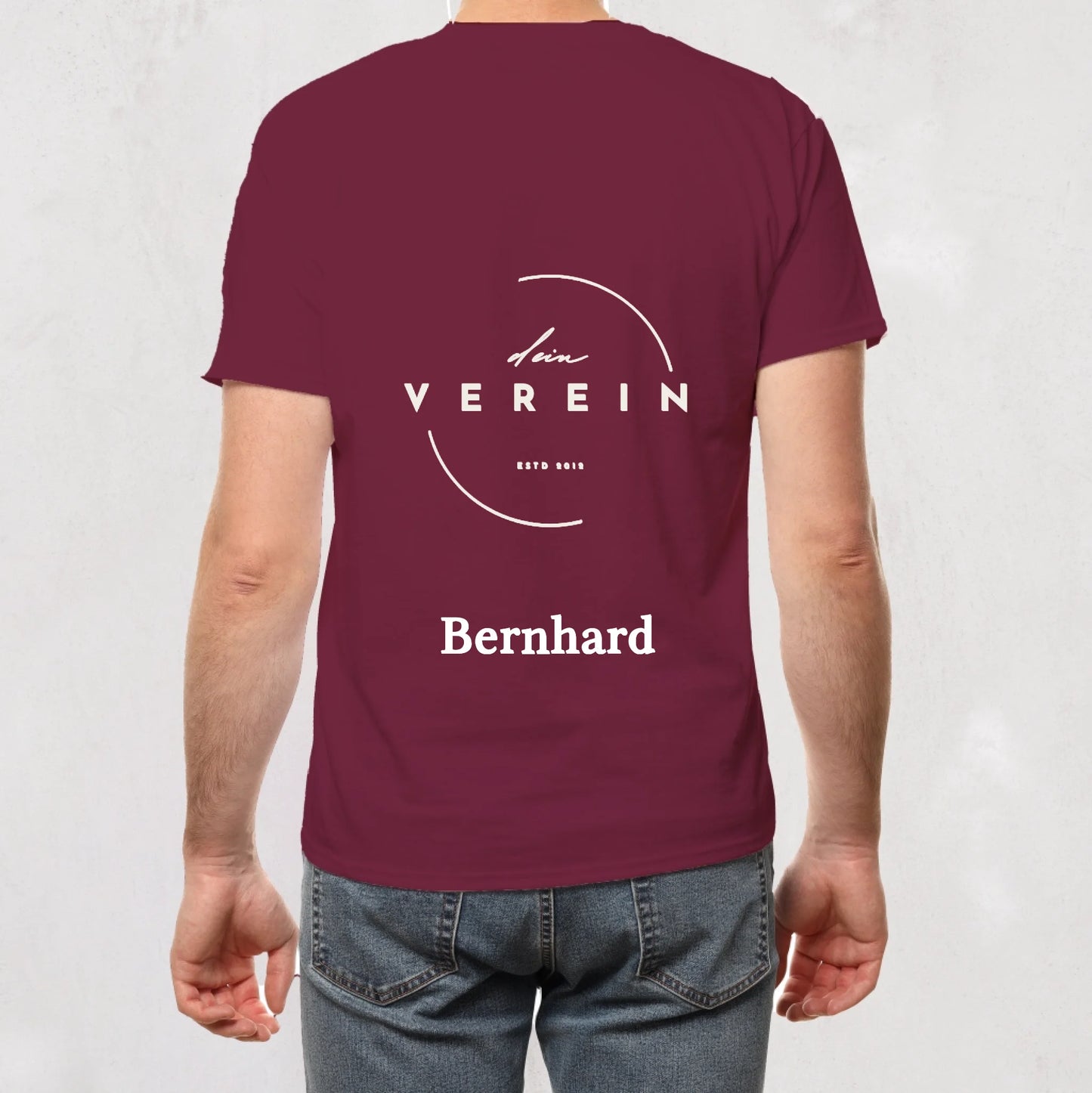 weinrotes T-Shirt mit Vereinslogo und dem Schriftzug ‚dein Verein – seit 2018‘ auf der Rückseite. Unterhalb des Logos steht ein personalisierbarer Name. Vereinsname und Name können individuell angepasst werden.